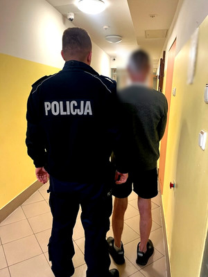 Policjant z zatrzymanym w pomieszczeniu dla osób zatrzymanych.