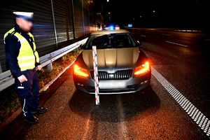 Policjant stojący przy zabezpieczonym aucie na autostradzie A-1.