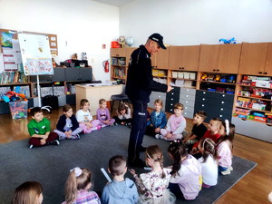 Policjant wręczający dzieciom elementy odblaskowe.