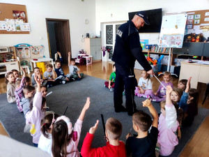 Policjant wręczający dzieciom elementy odblaskowe.