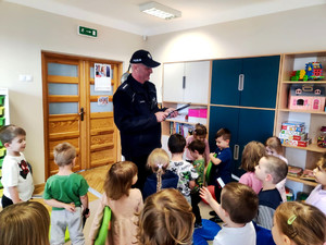 Policjant wręczający dzieciom elementy odblaskowe.