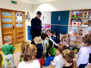 Policjant wręczający dzieciom elementy odblaskowe.