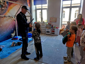 Policjant wręczający dzieciom elementy odblaskowe.