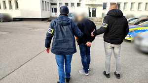 Policjanci z zatrzymanym na dziedzińcu komendy.