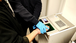 Policjant  pobiera od zatrzymanego odciski palców.