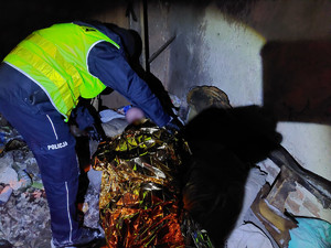 Policjant sprawdzający pustostany z osoba w kryzysie bezdomności.