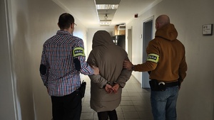 Policjanci z zatrzymaną stojący na korytarzu.