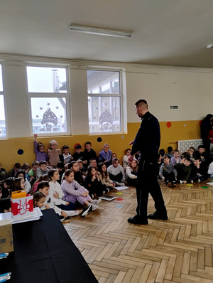 Dzielnicowy z dziećmi podczas prelekcji.
