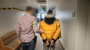 Policjant trzyma zatrzymanego mężczyznę.