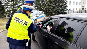 Policjanci podczas kontroli drogowej wręczają odblaskowe serca.