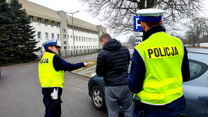 Policjanci podczas kontroli drogowej wręczają odblaskowe serca.