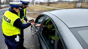 Policjanci podczas kontroli drogowej wręczają odblaskowe serca.