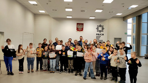 Policjanci z dziećmi podczas ferii w komendzie.