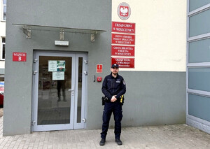 Policjant przed budynkiem Gminnego ośrodka Pomocy Społecznej w Moszczenicy.