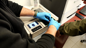 Policjant pobiera od zatrzymanego odciski palców.