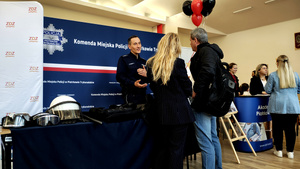 Policjant z kobietą i mężczyzną przy stoisku promocyjnym.