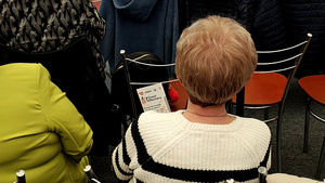 Seniorka trzymająca ulotkę.