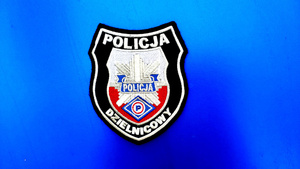 Tarcza z napisem Policja dzielnicowy na niebieskim tle.